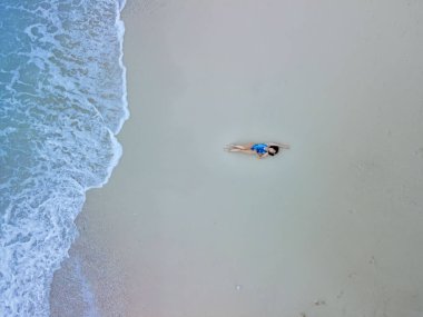 Deniz kıyısındaki mavi mayo giymiş güzel dalgalar.