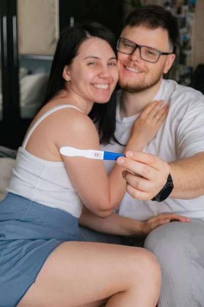 happy couple looking at positive pregnancy test copy space