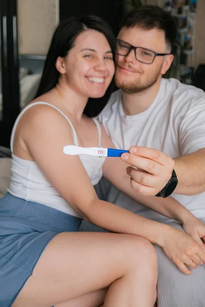 happy couple looking at positive pregnancy test copy space