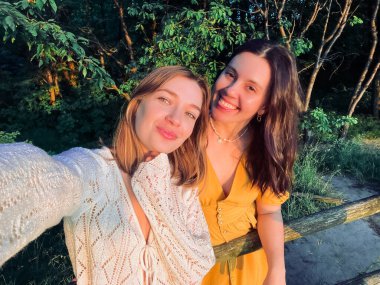 Bir çift kadın gün batımında selfie çekiyor.