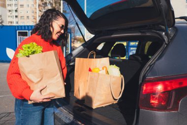 Kadın paketleri araba bagajına koydu. Alışveriş yapıyordu.