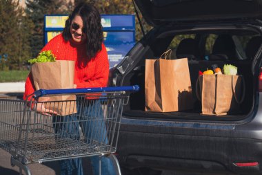 Kadın paketleri araba bagajına koydu. Alışveriş yapıyordu.