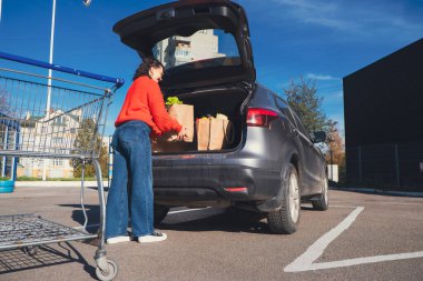 Kadın paketleri araba bagajına koydu. Alışveriş yapıyordu.