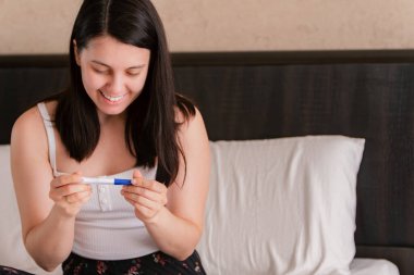 Mutlu kadın pozitif hamilelik testi gösteriyor. Yakın plan.