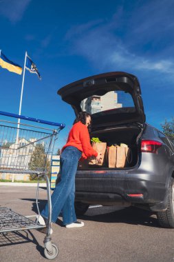 Kadın paketleri araba bagajına koydu. Alışveriş yapıyordu.