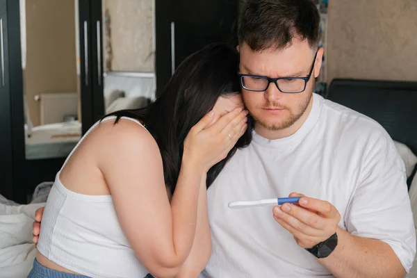 worried couple looking at positive pregnancy test unwanted