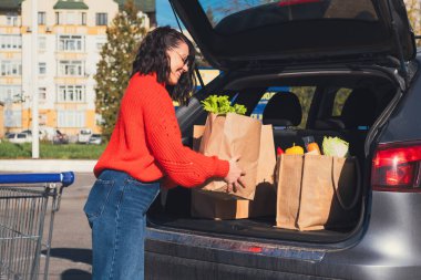 Kadın paketleri araba bagajına koydu. Alışveriş yapıyordu.