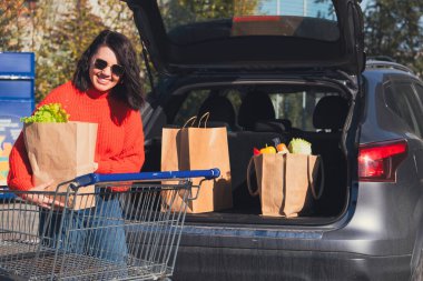 Kadın paketleri araba bagajına koydu. Alışveriş yapıyordu.