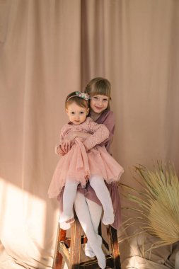 Sevimli kız kardeşlerin portresi. Çocuklar sarılıp gülümsüyor.