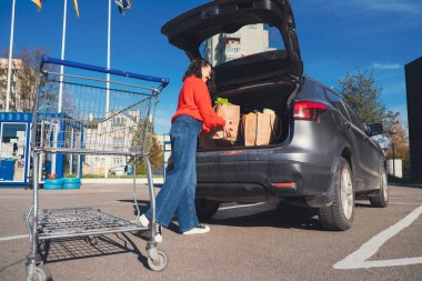 Kadın paketleri araba bagajına koydu. Alışveriş yapıyordu.