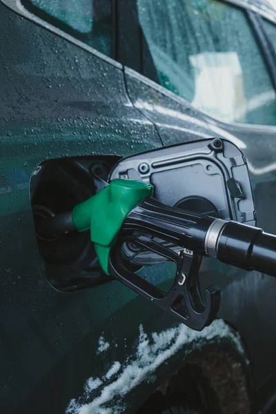 In fuel tank of car, a gas pump nozzle. winter season
