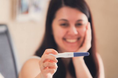 Mutlu kadın pozitif hamilelik testi gösteriyor. Yakın plan.