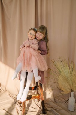 Sevimli kız kardeşlerin portresi. Çocuklar sarılıp gülümsüyor.