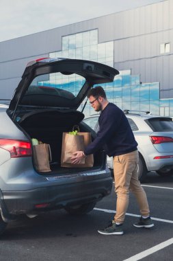 Mutlu adam alışveriş merkezinin otoparkına erzak poşeti koydu.