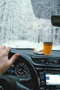 Direksiyonda erkekler, gösterge panelinde hamburger ve kahve ve kış yolu var..