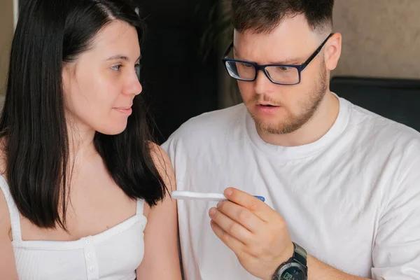 worried couple looking at positive pregnancy test unwanted