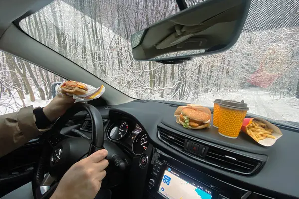 lunch stop in winter forest, happy man eats while driving car.