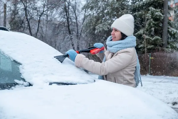 woman clean car out of snow after night blizzard snowstorm