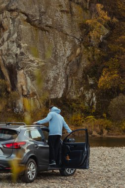 Erkek araba yolcusu River Rock Plajı 'nda durur sonbahar ormanlarının tadını çıkarır.