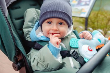 Bahar parkında bebek arabasında gülümseyen bebek.