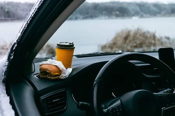 burger and coffee mug at car dashboard copy space