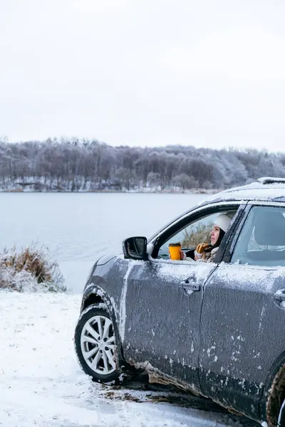 woman eat burger sitting in car at the frozen lake beach copy space