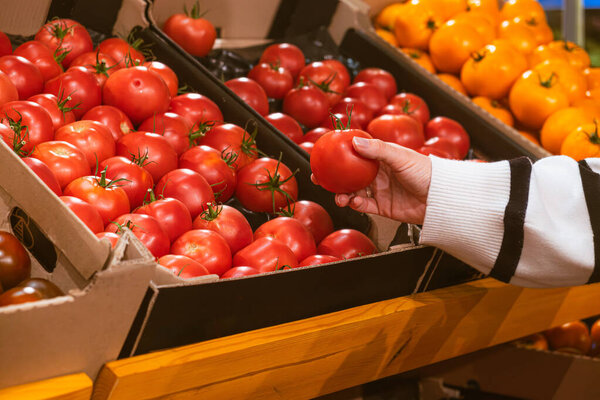 hand taking tomatoes from grocery store shelf copy space