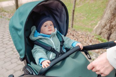 Bahar parkında bebek arabasında ciddi bir bebek.