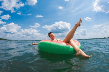 Şişme havuzda takılan mutlu kadın yaz güneşli bir günde yüzüyor.