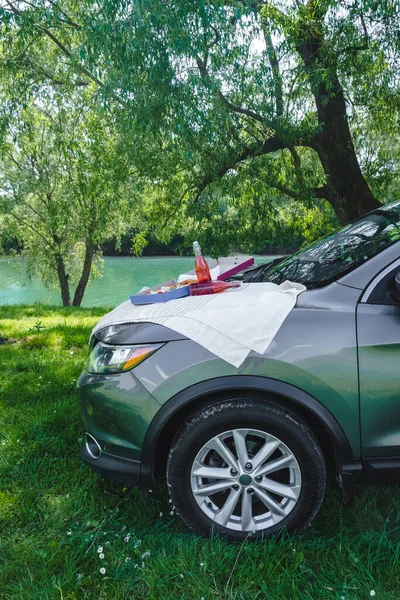 outdoors picnic pizza with drink on car hood at the river side summer time