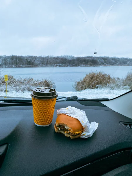burger and coffee mug at car dashboard copy space