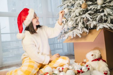 Mutlu gülümseyen kadın evde Noel ağacı süslüyor.