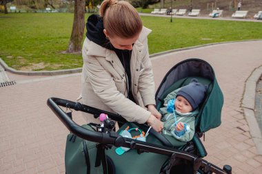 Anne oğlunu bebek arabasında emniyet kemerleriyle bağlayacak.