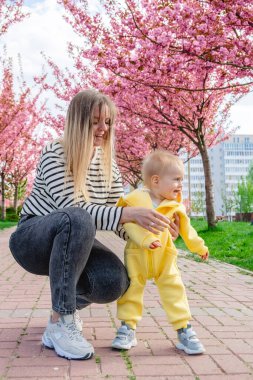 Bebek annesinin elini tutarak yürümeyi öğreniyor.