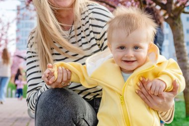 Bebek annesinin elini tutarak yürümeyi öğreniyor.