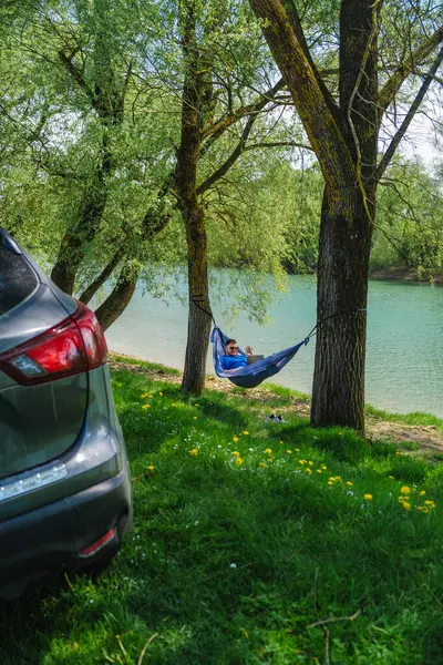 Relaxing work environment: man in hammock with laptop by river