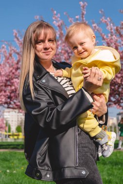 Mutlu anne, baharda çiçek açan kiraz ağaçlarının yanında ellerini tutuyor.