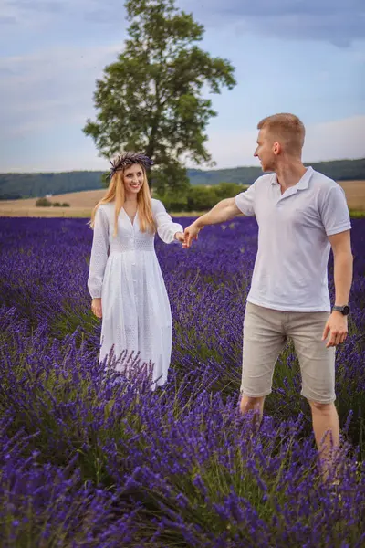 a couple in love is walking in a lavender field. cloudy sky