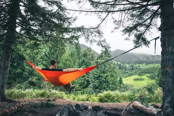 man in hammock at camping site mountains on background copy space