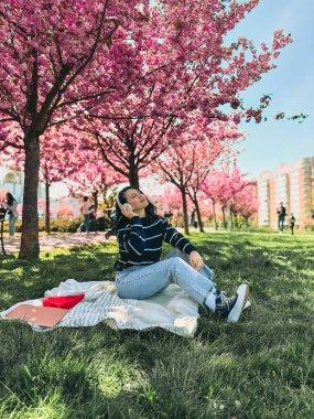 Tarz sahibi kadın meloman müzik dinliyor. Arka planda sakura açan boşluğu kopyalıyor.