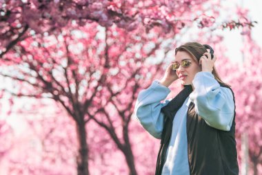 Tarz sahibi kadın meloman müzik dinliyor. Arka planda sakura açan boşluğu kopyalıyor.