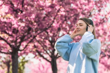 Tarz sahibi kadın meloman müzik dinliyor. Arka planda sakura açan boşluğu kopyalıyor.