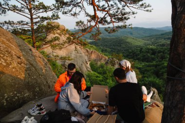 Mutlu arkadaşlar uçurumda pizza yiyorlar güzel Karpat dağ manzaralı