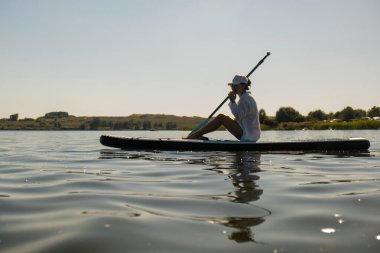 Sakin bir gölde yaz mevsiminde Serene Paddleboard yapan kadın