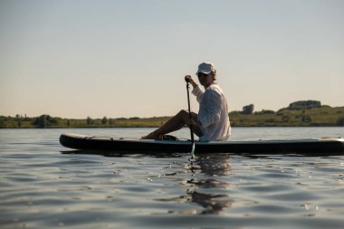 Sakin bir gölde yaz mevsiminde Serene Paddleboard yapan kadın