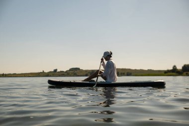 Sakin bir gölde yaz mevsiminde Serene Paddleboard yapan kadın