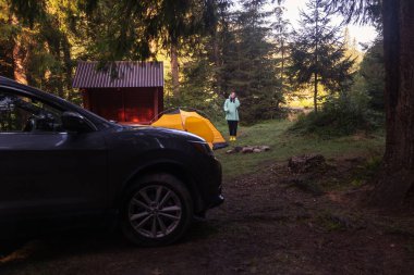 Ormanın ortasında çadırın yanında duran Ormandaki Huzurlu Kamp Sahnesi