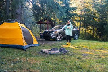 Arka planda Serene Forest SUV 'de sabah kahvesi içen mutlu bir kadın.