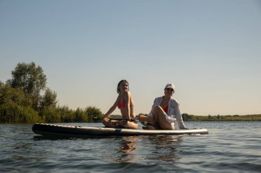 Women Enjoying Paddleboarding on a Sunny Day summertime clipart