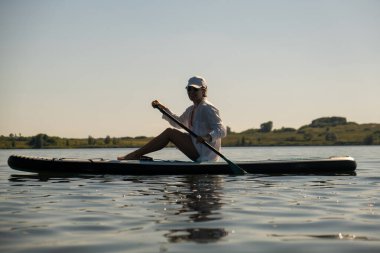Sakin bir gölde yaz mevsiminde Serene Paddleboard yapan kadın